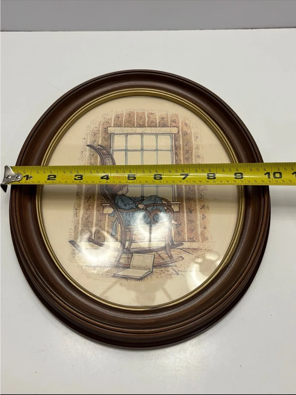Vintage oval framed wall art piece featuring a girl in a rocking chair by a wind